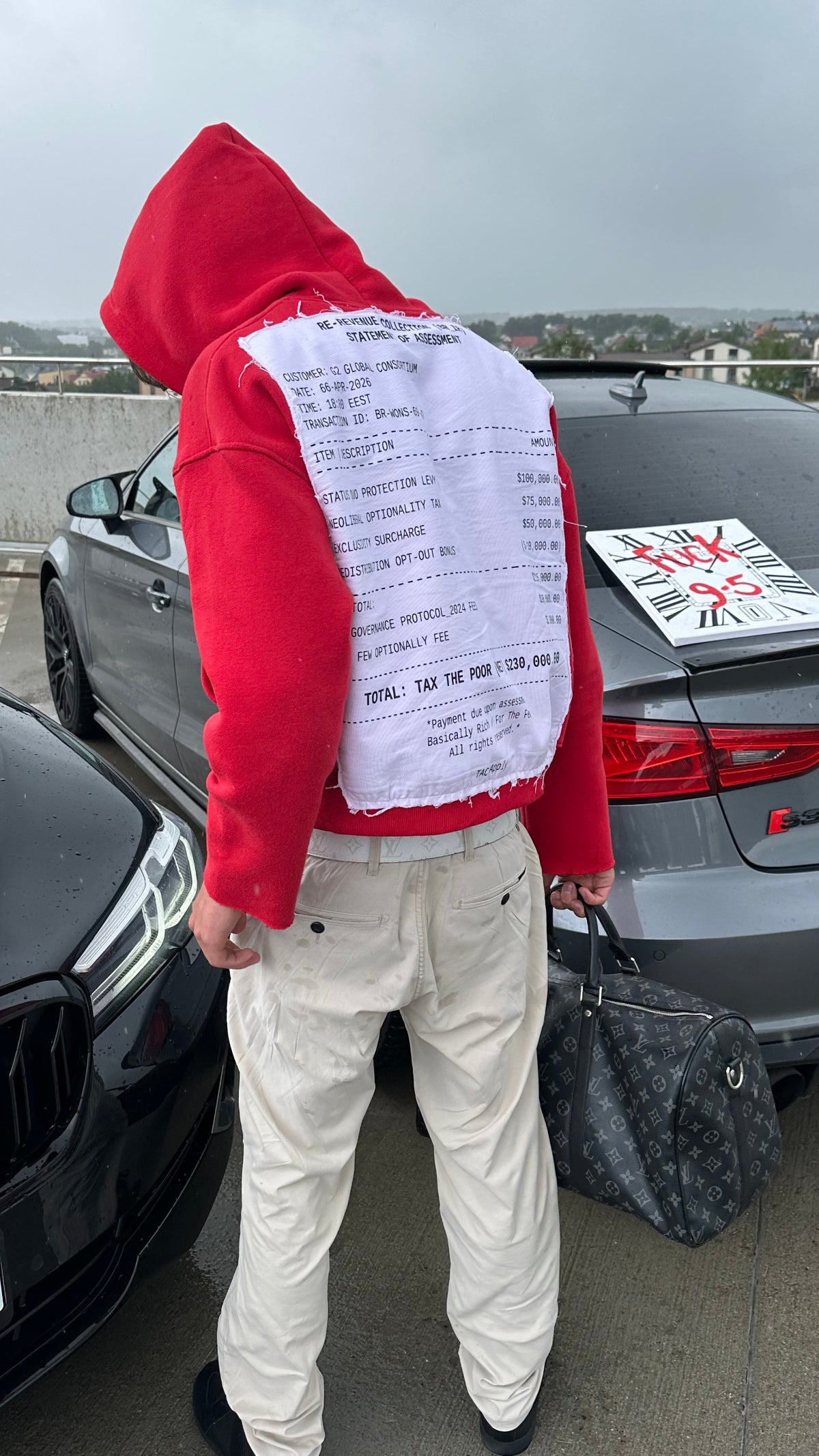 Person wearing a red hoodie with a white shirt underneath, standing next to a car with a visible license plate.